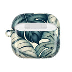 AirPods Pro case with a tropical leaf pattern, featuring large, stylized green and cream monstera leaves. The case is open and empty.