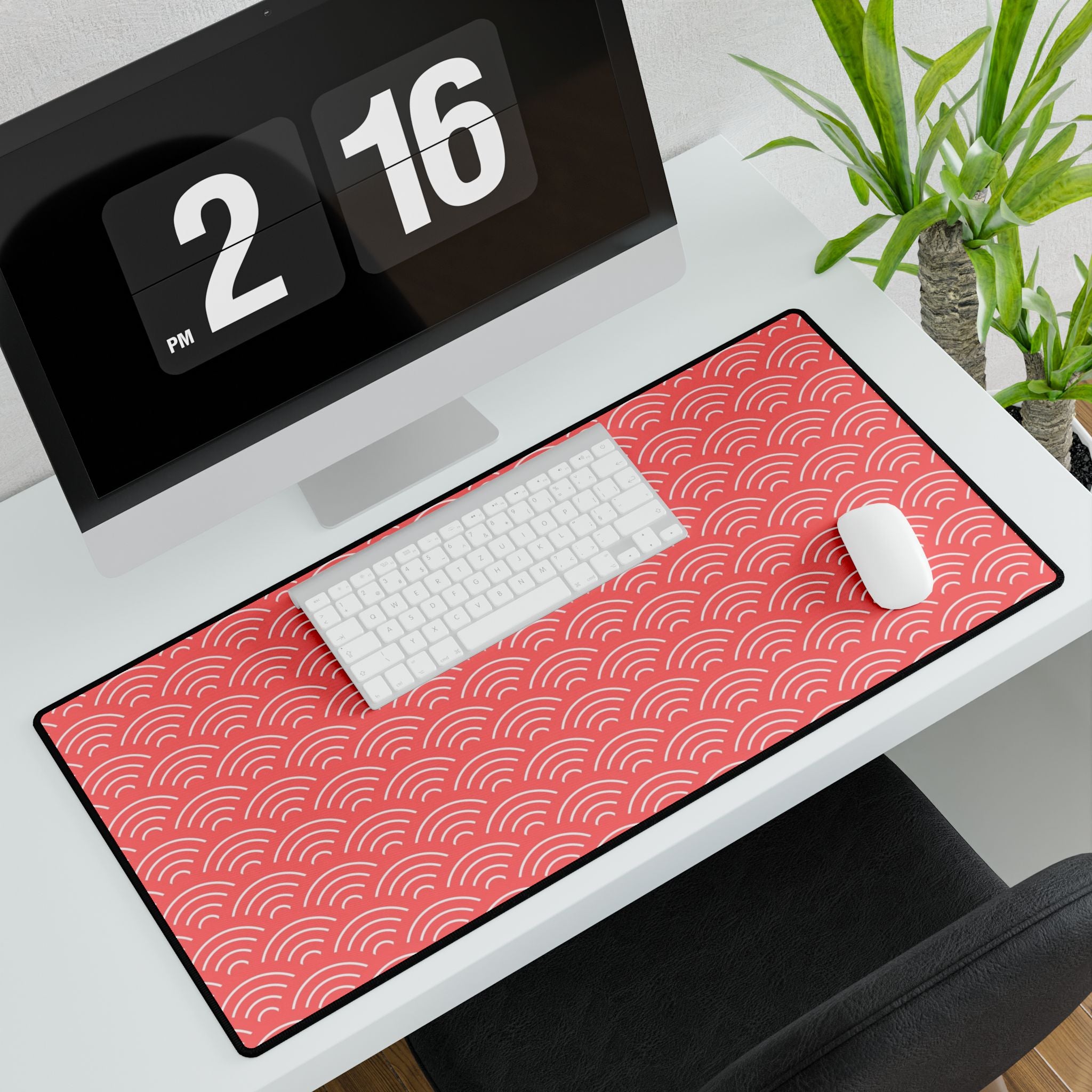 Desk setup with a red patterned mouse pad, keyboard, and computer monitor.