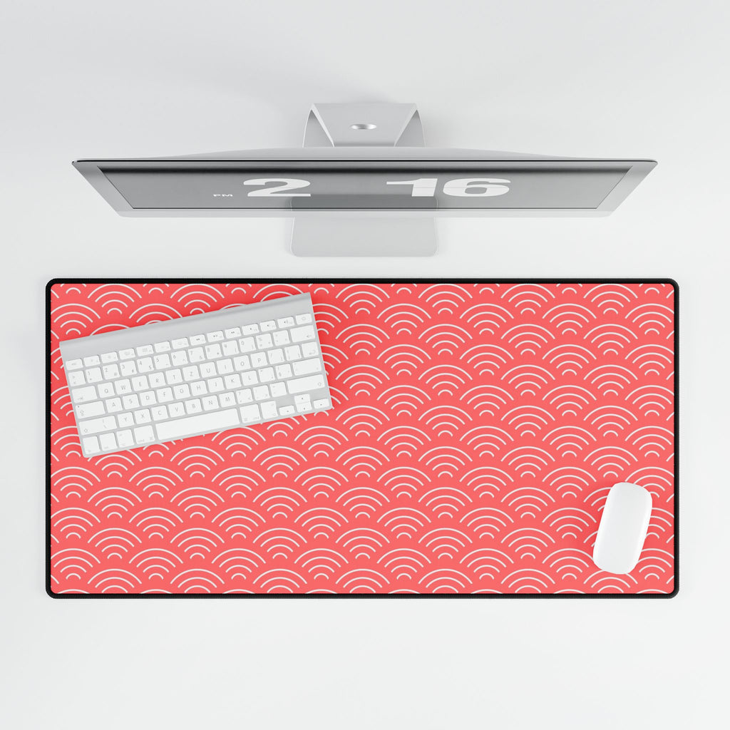 Red desk mat with white wave pattern on a white surface, featuring a computer monitor and keyboard.