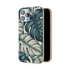 A slightly angled view of a beige, speckled iPhone case with a teal and blue monstera leaf pattern. The case is open, revealing its smooth brown interior and the triple camera cutout at the top.