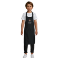 Child wearing a black apron with 'Archie' printed on it against a white background