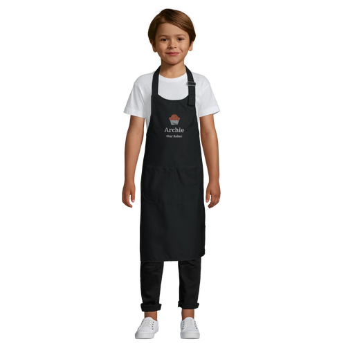 Child wearing a black apron with 'Archie' printed on it against a white background