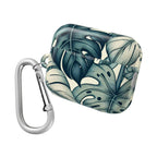 AirPods Pro case with a tropical leaf pattern, featuring large, stylized green and cream monstera leaves. The case is closed and a large silver metal carabiner clip is attached to the side loop.