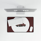 Desk setup with a monitor, keyboard, mouse, and car model on a desk pad.