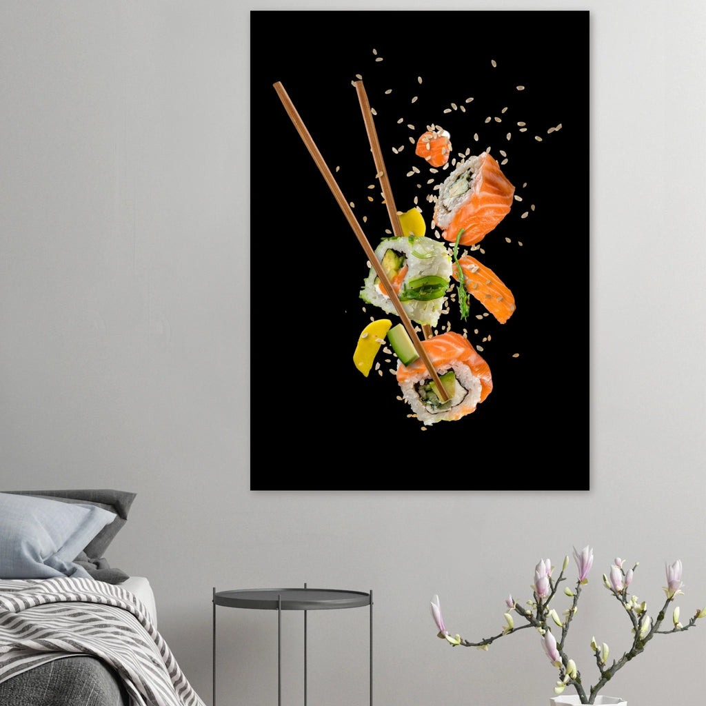 Wall poster showing sushi pieces suspended mid-air with chopsticks, sesame seeds and ingredients scattering against a black background, displayed in a minimalist bedroom interior.