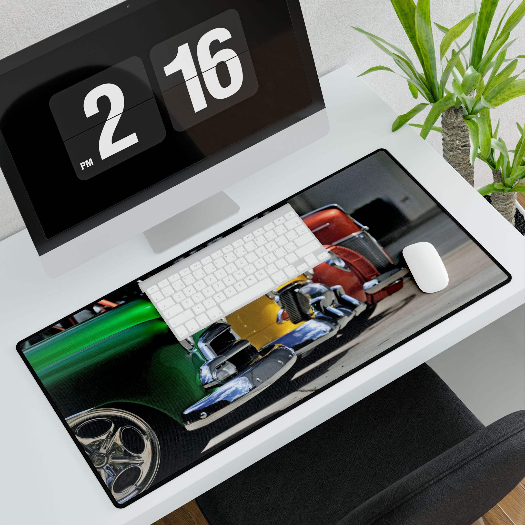Desk setup with a mouse pad featuring car designs, a keyboard, and a computer monitor.