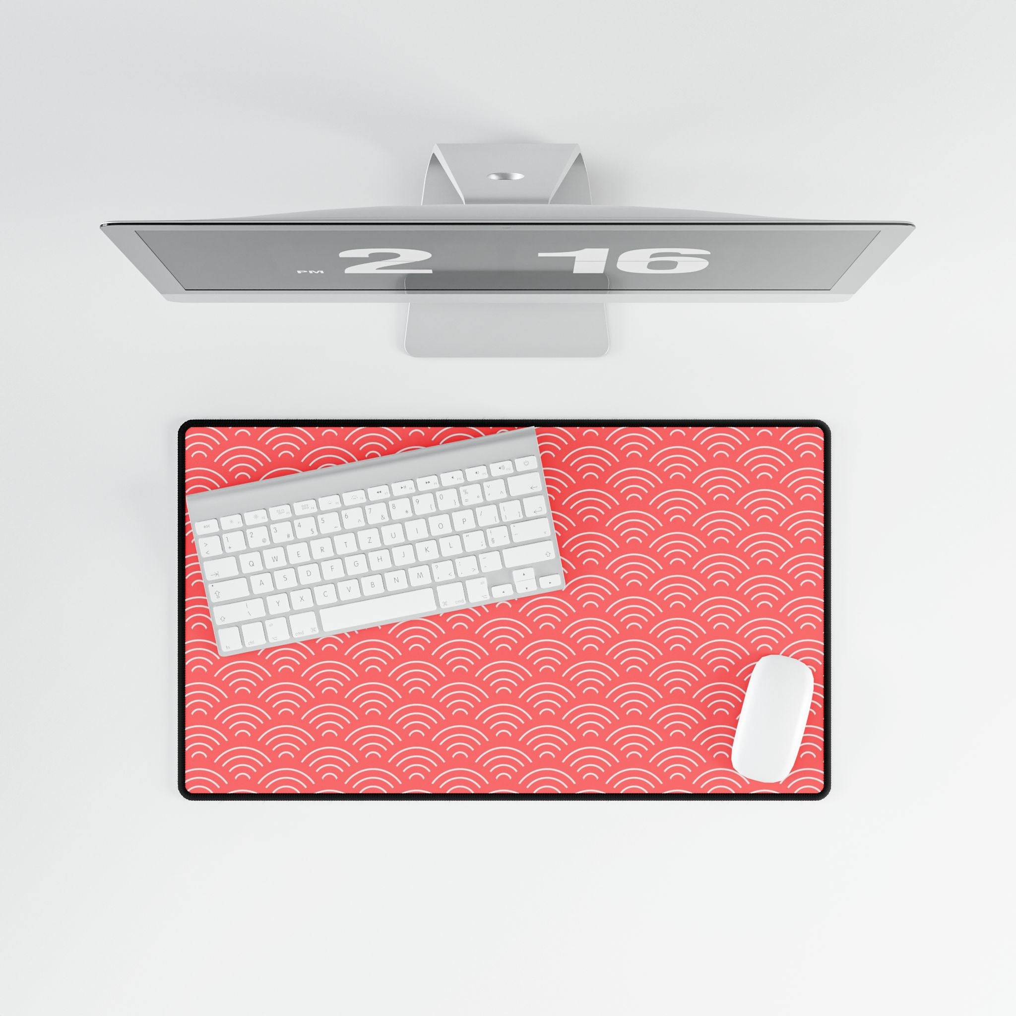 Desk setup with a red patterned desk mat, keyboard, mouse, and computer monitor on a white background.