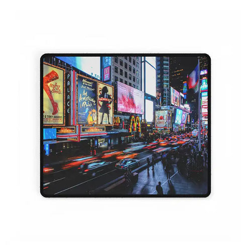New York Times Square at night with bright billboards, busy traffic light trails, and pedestrians walking along the street, displayed as an MVB Studio mouse pad design.