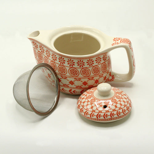 Ceramic teapot with red floral patterns, mesh filter, and lid on a white background