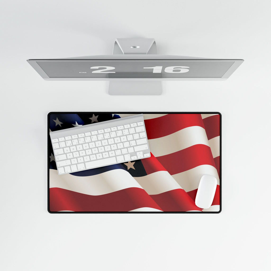 Desk setup with a computer monitor, keyboard, and mouse pad featuring an American flag design on a white background.