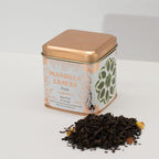 Tea tin labeled 'Mandala Leaves' with loose tea leaves on a white background