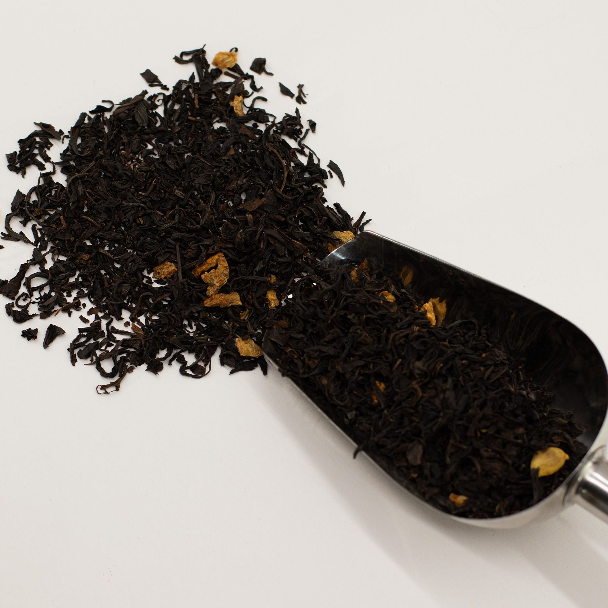 Black Tea with Orange Peel Citrus Loose Leaf Tea in a metal scoop on a white background