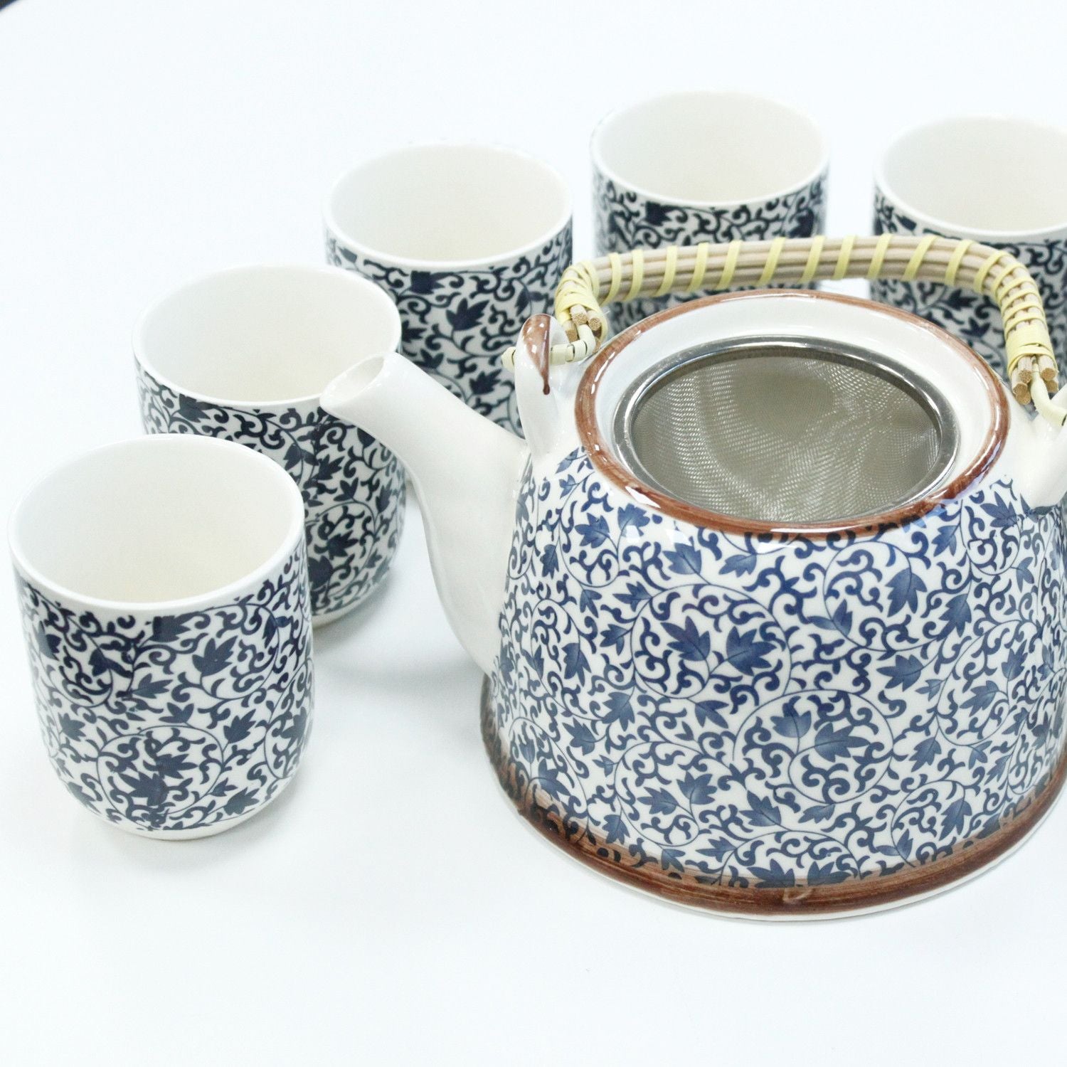 Ceramic teapot and cups with blue floral patterns on a white background