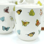 Ceramic mug with colorful butterfly designs on a white background