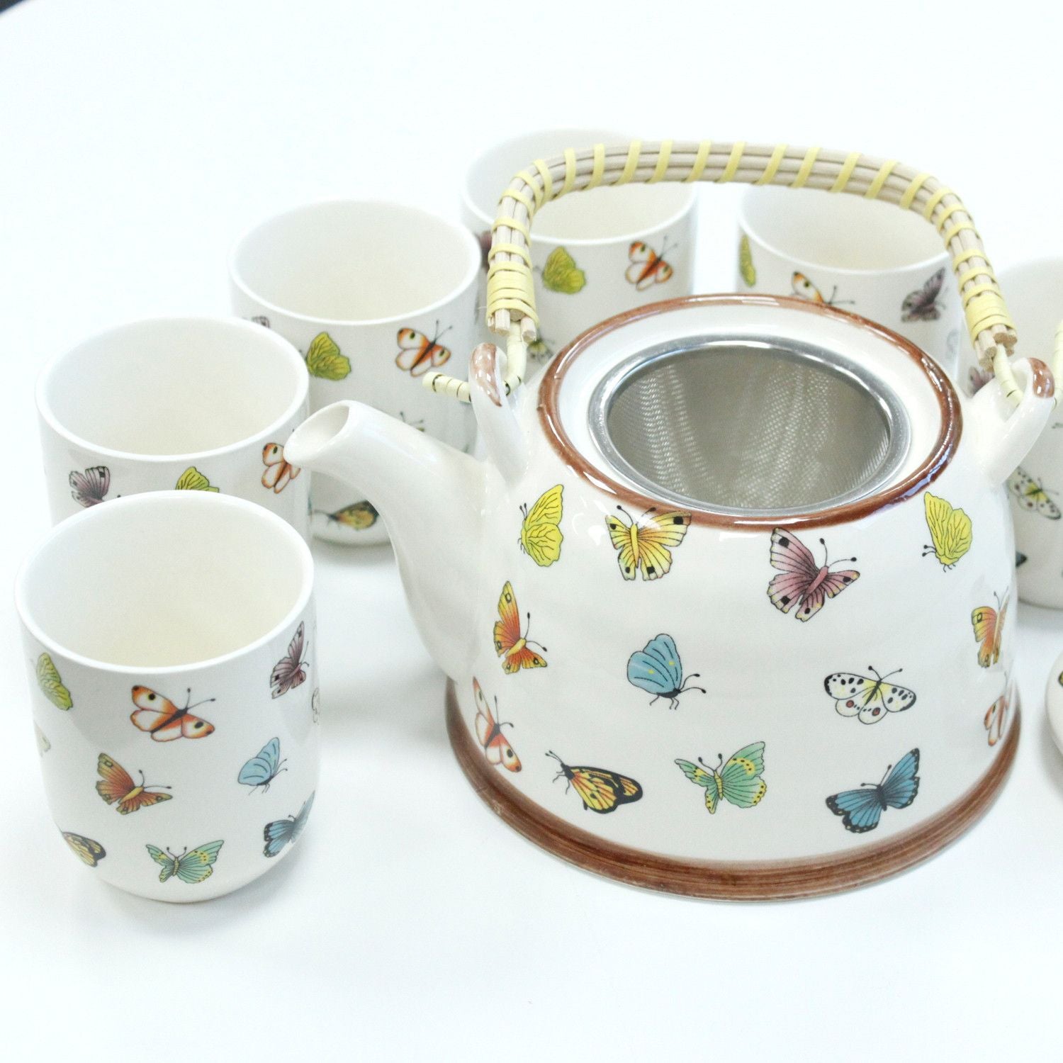 Ceramic teapot and cups with butterfly design on a white background