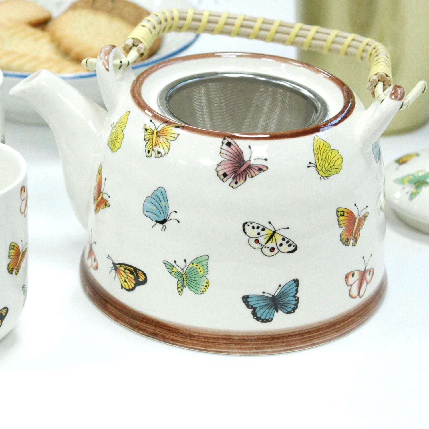 Ceramic teapot with butterfly designs on a white surface from MVB STUDIO store.