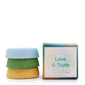 Three colorful bath fizzers stacked with a box labeled 'Love & Truth' on a white background.