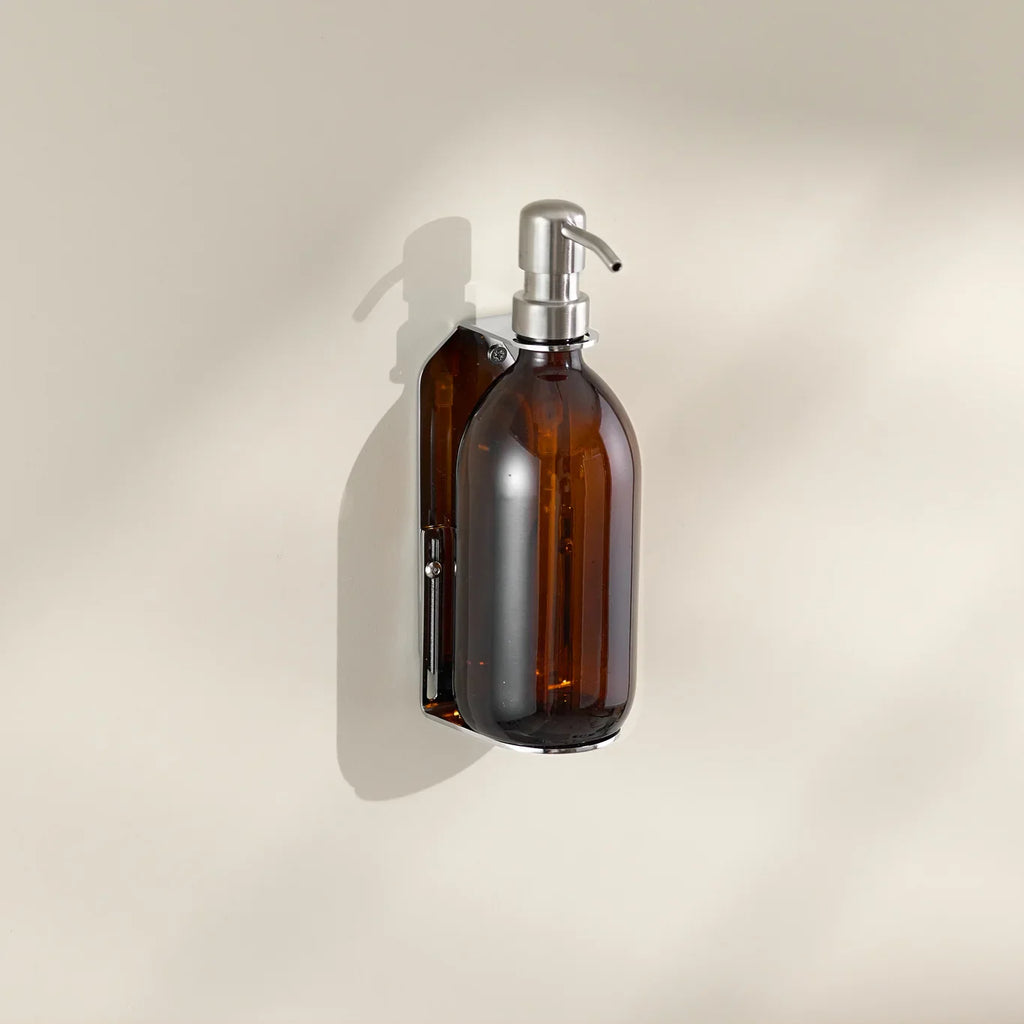 Amber glass bottle with silver pump on a beige background