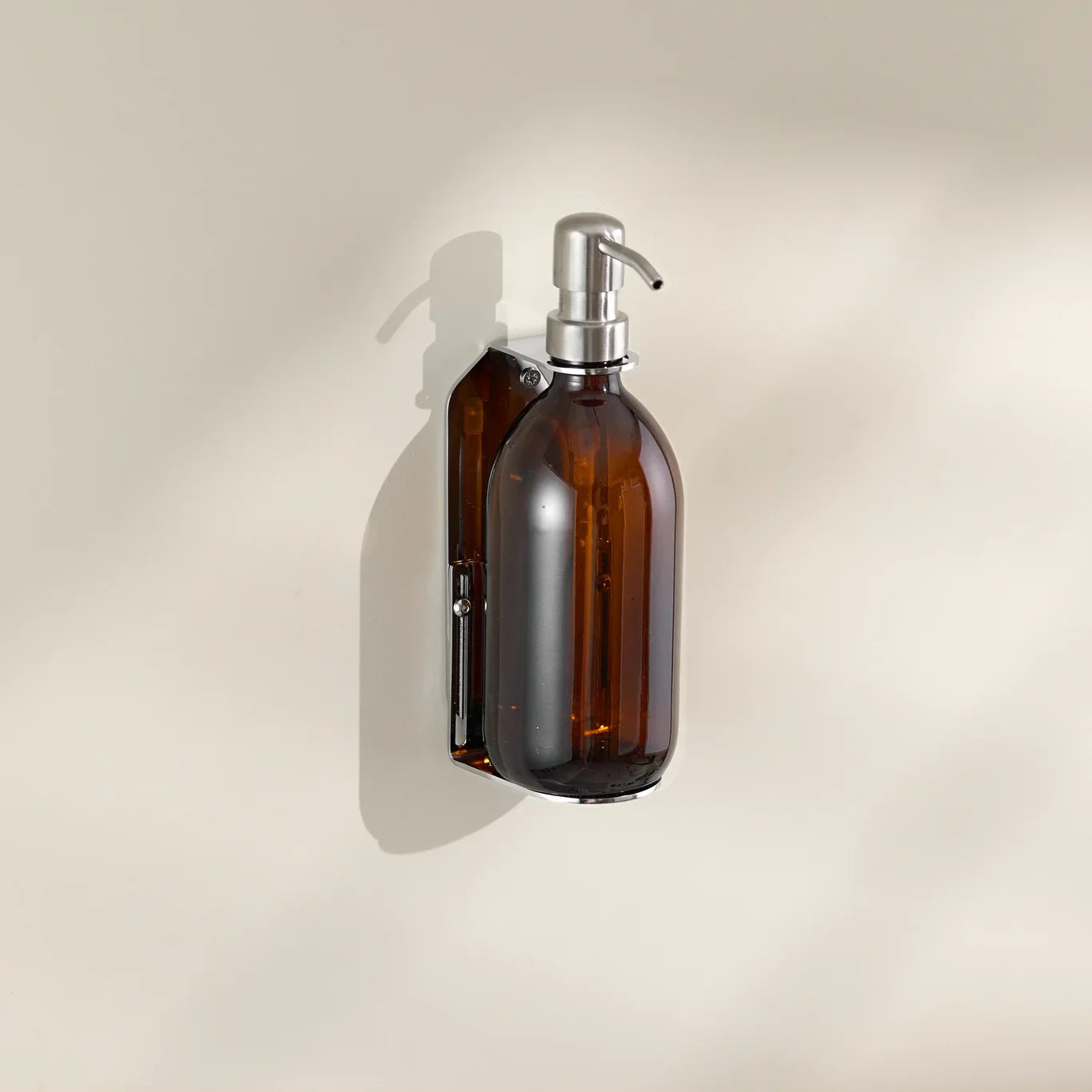 Amber glass bottle with silver pump on a beige background
