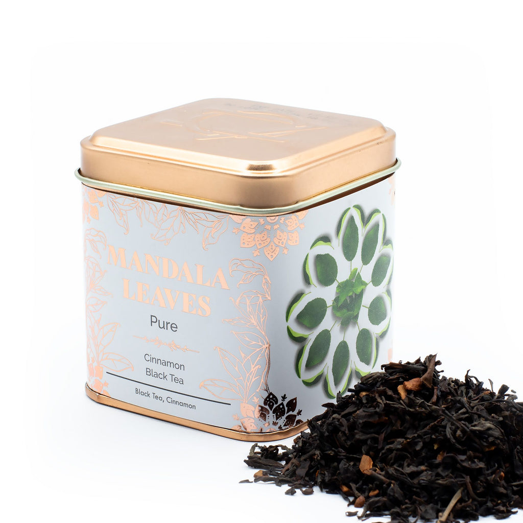 Tea canister labelled 'Mandala Leaves' with Cinnamon Black Tea spilling out on a white background