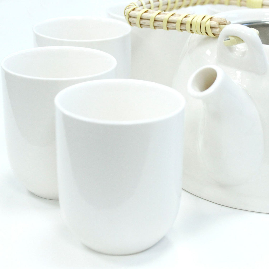 Set of white ceramic tea cups and a teapot on a white background