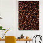 Framed picture of coffee beans on a wall above a table with chairs.