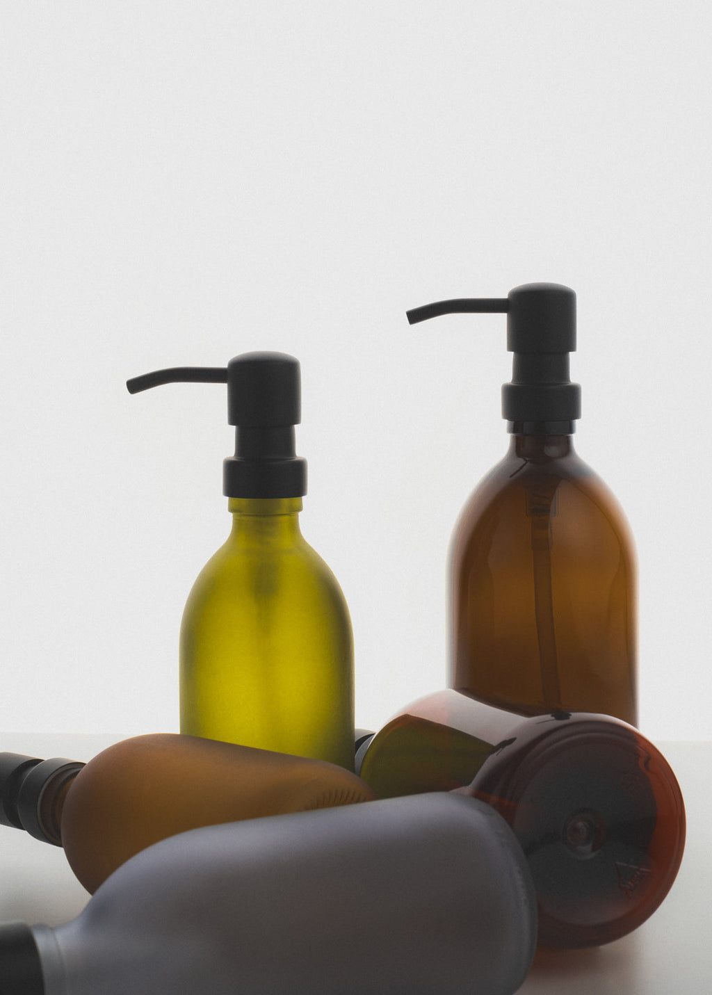 Three brown glass bottles with pump dispensers on a white background