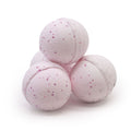 Three pink bath bombs with speckles on a white background
