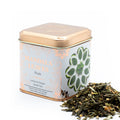 Tea tin labeled 'Mandala Leaves' with Ginger & Lemon Green Tea Sencha Blend 50g spilling out on a white background