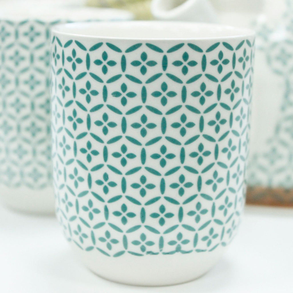 White mug with teal geometric pattern on a white background