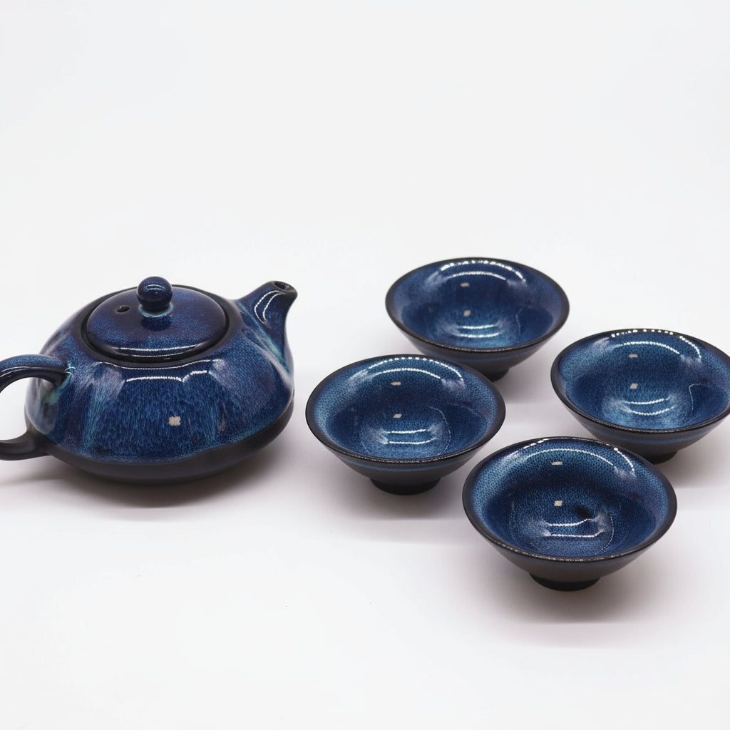 Blue ceramic teapot and four matching cups on a white background