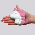 Unicorn-shaped bath bomb held in a hand against a plain background