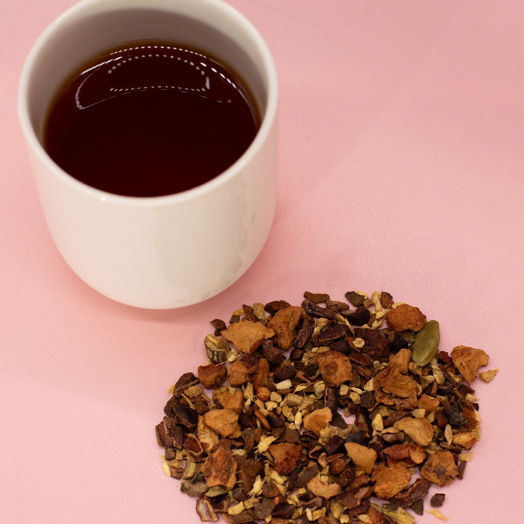 White cup of black tea with a Hot Chocolate Chai Infusion - 50g on a pink background
