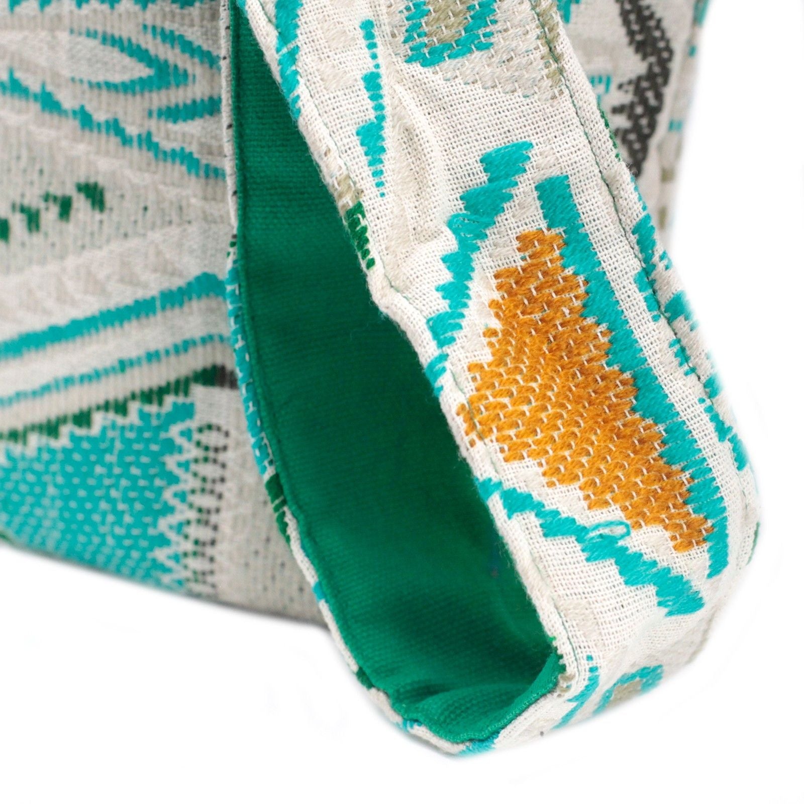 Close-up of a fabric with green, orange, and white pattern on a white background