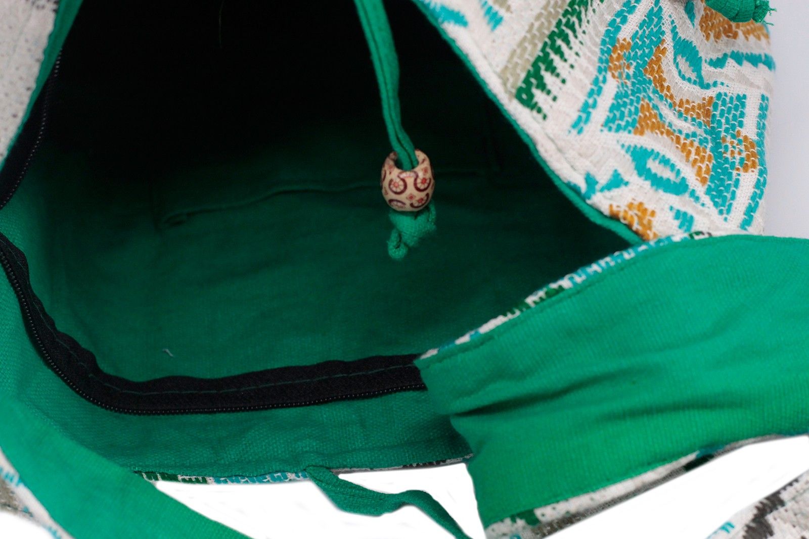 Close-up of a green drawstring bag with a decorative pattern on a white background