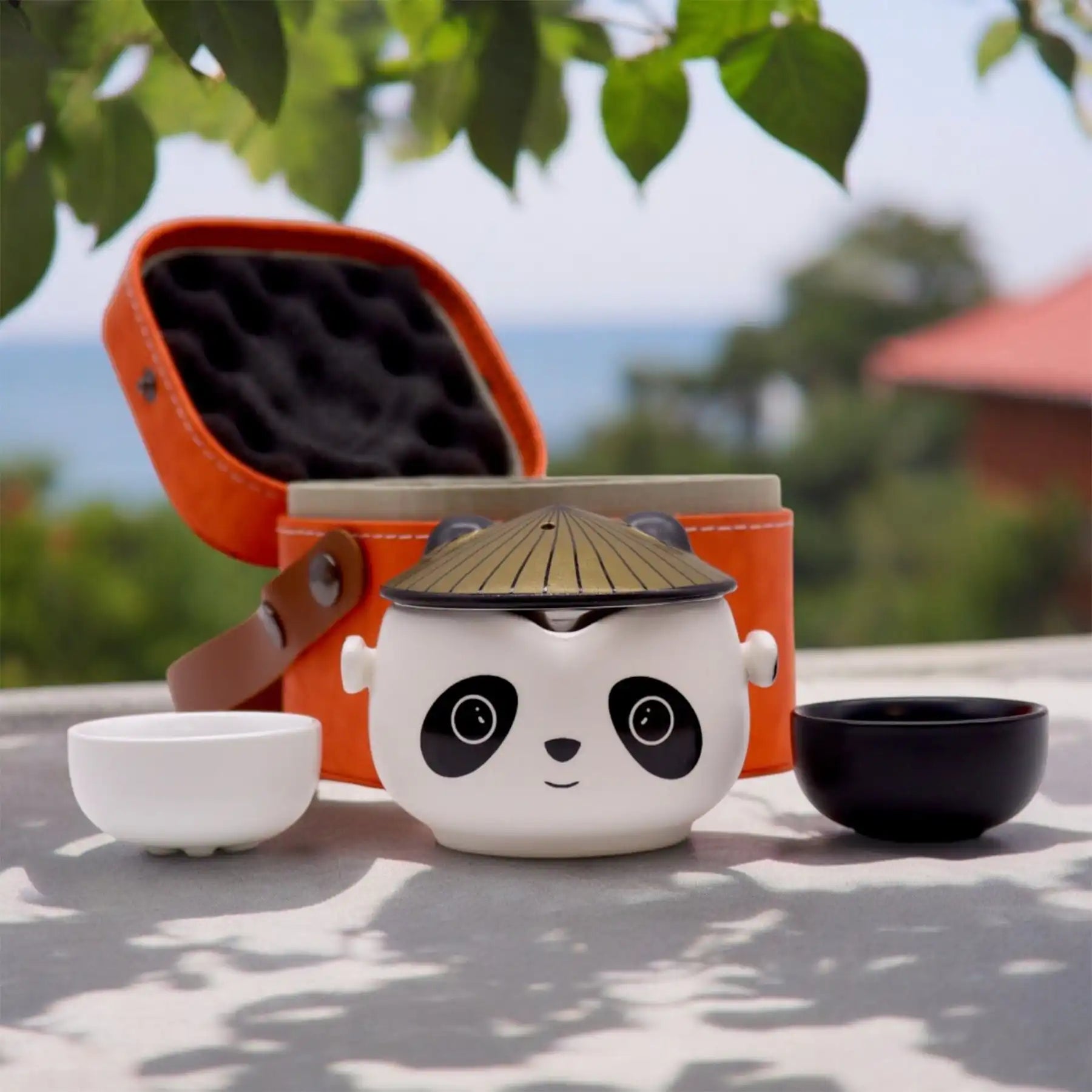 Cute panda-shaped tea set with a bamboo lid on a table outdoors.