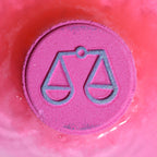 Pink bath bomb with Libra zodiac symbol on a pink background