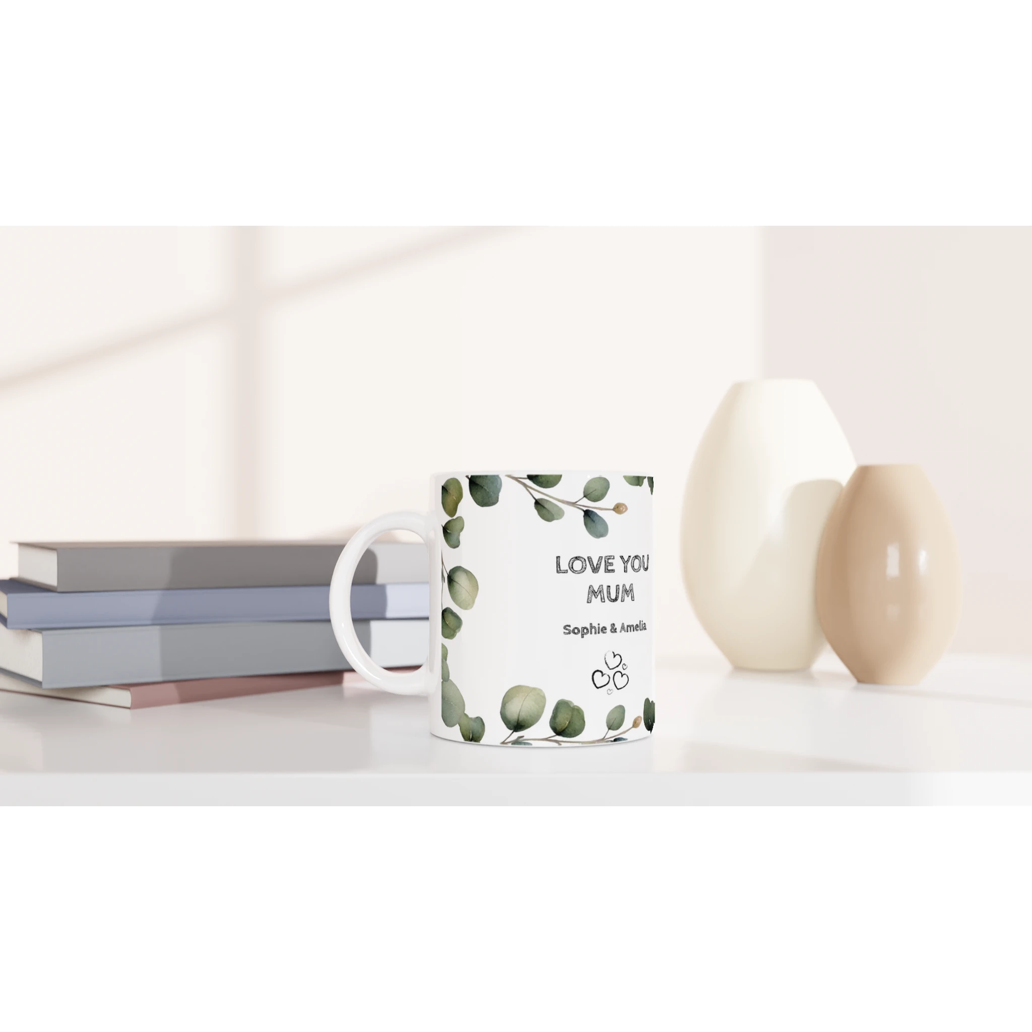 Mug with 'Love You Mum' text on a white surface with books and decorative items.