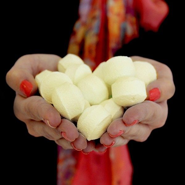 Hands holding white marshmallows against a dark background