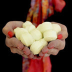 Hands holding white marshmallows against a dark background