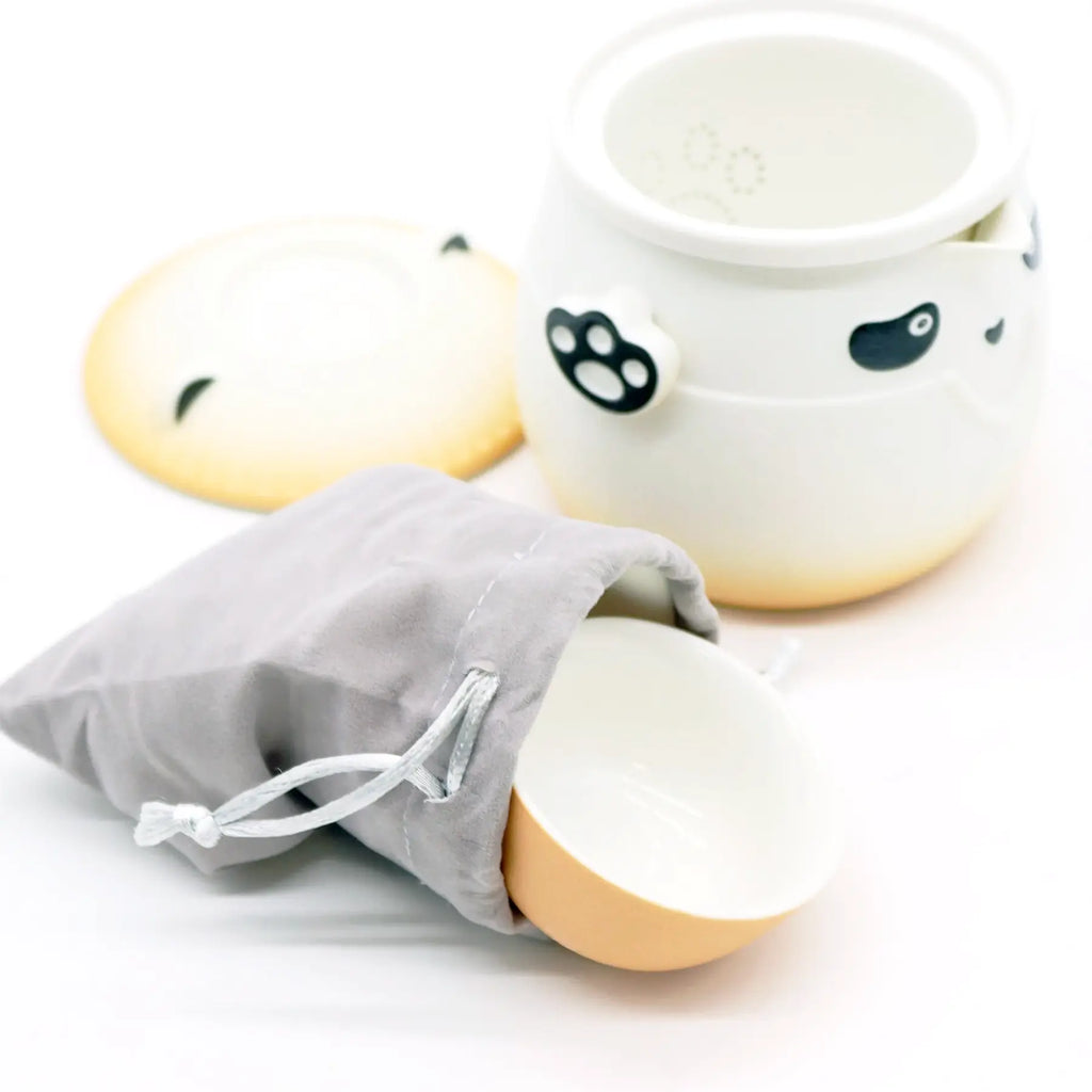 Two white ceramic bowls with black paw prints and a gray drawstring bag on a white background