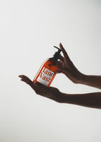 Hand holding a Plastic Bottle Dispensers of hand wash against a light background
