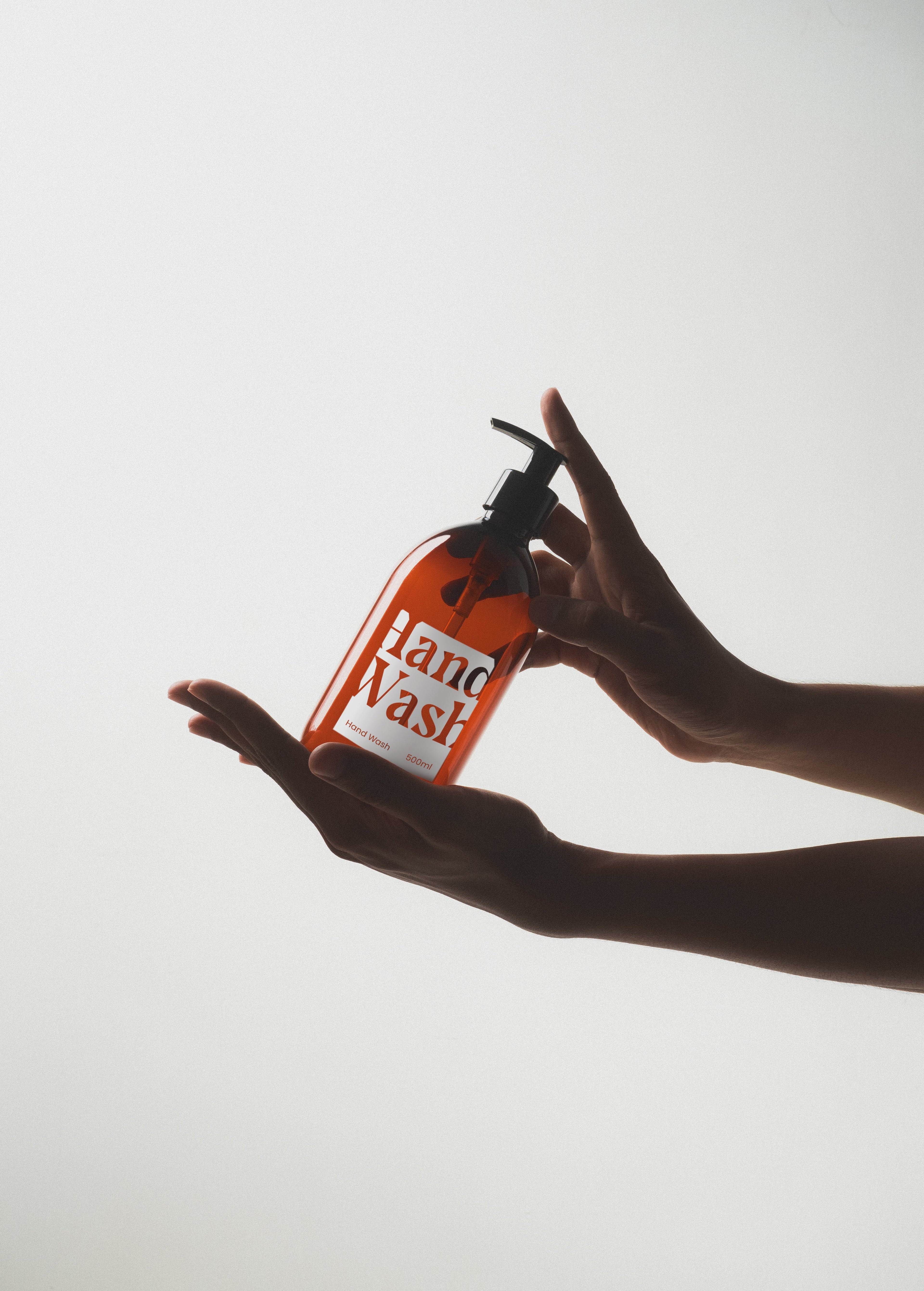 Hand holding a Plastic Bottle Dispensers of hand wash against a light background