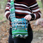 Person holding a colorful patterned Teal Sling Jacquard Bag with a blurred natural background