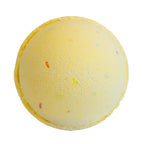 Yellow bath bomb with specks on a white background