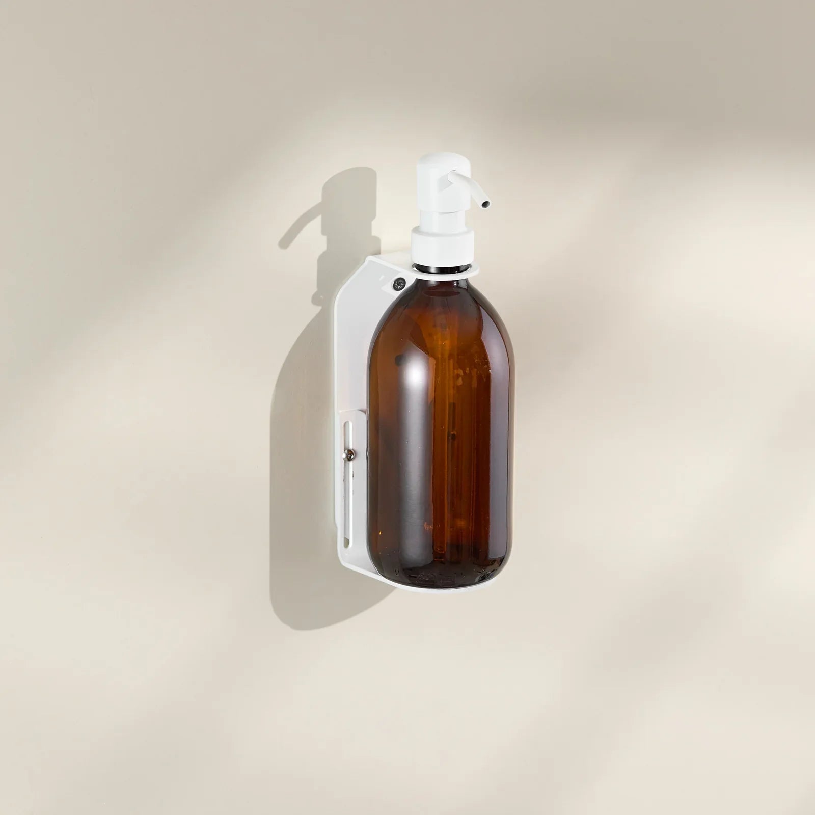 Brown glass spray bottle with white nozzle on a beige background