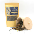 Artisan White Tea with Sencha, Apple & Cinnamon - 50g packaging with a wooden container of tea leaves on a white background