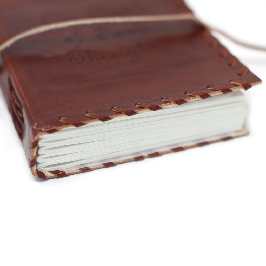 Brown leather notebook with white pages on a white background