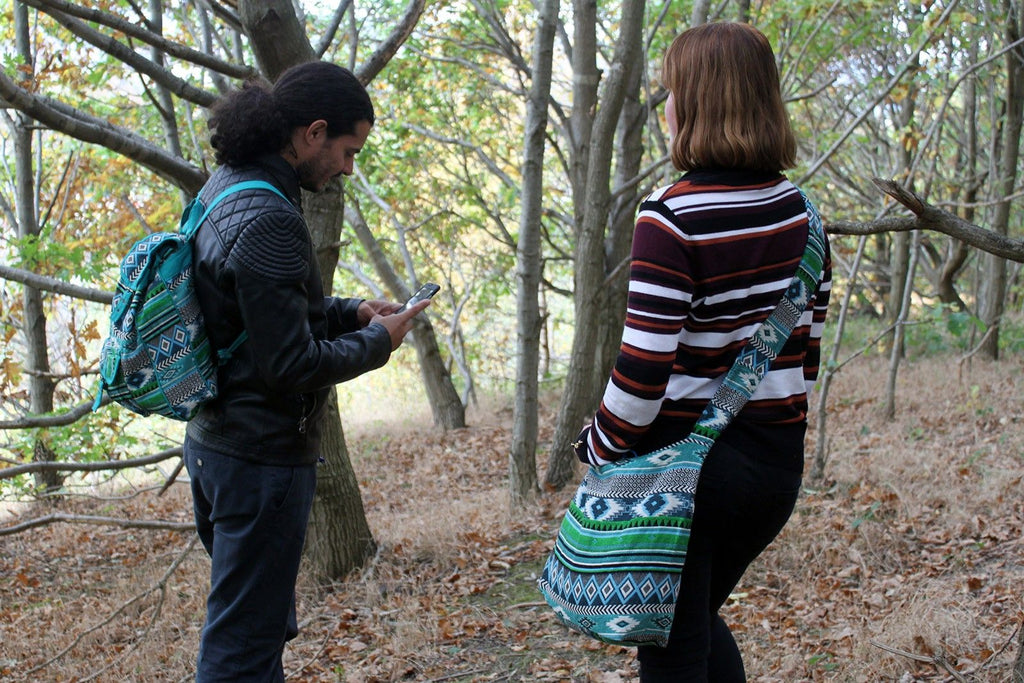 Jacquard Bag - Teal Student Bag being worn in nature by a couple with a backpack and sling bag.