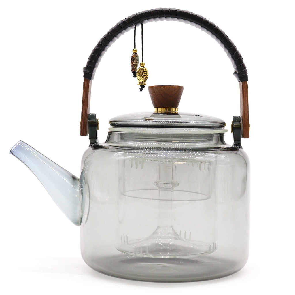 Clear glass teapot with wooden handle and black arch on a white background
